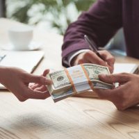 cropped view of businesspeople holding dollar banknotes, salary concept